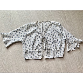 เสื้อลายเชอรร์รี่สีขาว เเต่งเชอร์รี่สีฟ้า มีเชือกผูกไคว้ด้านหน้า เเขนยาวประมาณศอกิเเต่งระบาย