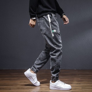 ☋♛✧กางเกงยีนส์เอวยางยืดผู้ชายทรงหลวม Harlan fall drawstring feet tooling trousers trend all-match casual