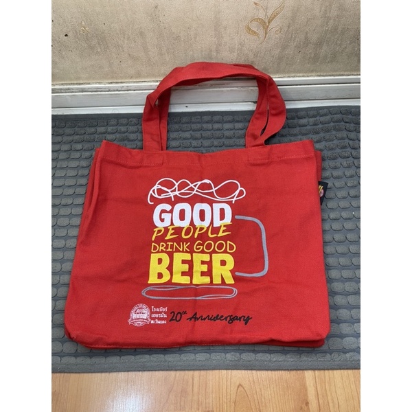กระเป๋าผ้าสีแดง มีโลโก้โรงเบียร์เยอรมันตะวันแดง