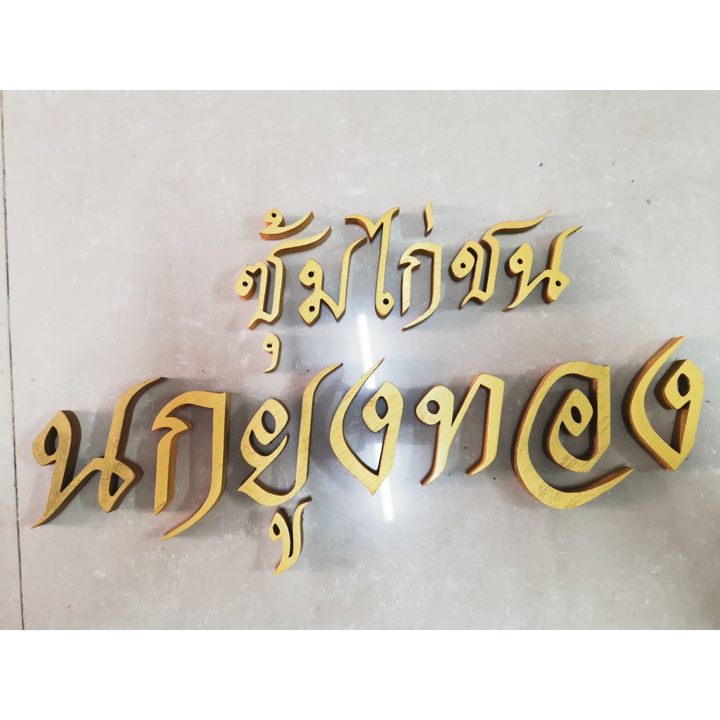 ตัวอักษรไม้สักแท้ " ซุ้มไก่ชน นกยูงทอง " ตัวอักษรภาษาไทย ไม้สักแกะสลัก ขนาดสูง 2 และ 3 นิ้ว ทาสีทอง