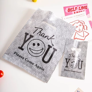 100 ใบ ถุงพลาสติกหูหิ้วลายหน้ายิ้มสีดำ THANK YOU แบบหนาและทนทาน เหมาะสำหรับใส่เสื้อผ้า ของขวัญ และสินค้า พกพาสะดวก หูหิ้วแข็งแรง ช่วยจัดของให้เป็นระเบียบ ใช้งานง่าย เหมาะสำหรับร้านค้า บูติก และการช้อปปิ้งในชีวิตประจำวัน เหมาะสำหรับการใช้งานทั่วไปในทุกวัน