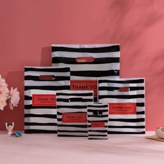 100 ใบ ถุงพลาสติกหูหิ้วลายทางขาวดำ THANK YOU สำหรับใส่ของขวัญและสินค้า เหมาะสำหรับช้อปปิ้งและแพ็กของ หูหิ้วแข็งแรง พกพาสะดวก ดีไซน์เรียบง่าย ช่วยจัดของให้เป็นระเบียบ เหมาะสำหรับร้านเสื้อผ้า บูติก ร้านของขวัญ และการใช้งานประจำวัน ใช้ได้สำหรับบ้านและร้านค้า
