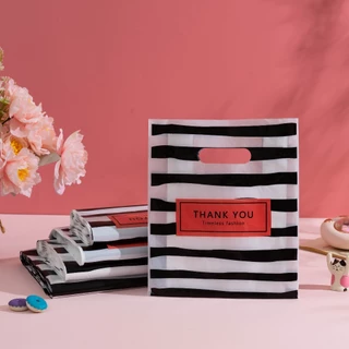 100 ใบ ถุงพลาสติกหูหิ้วลายทางขาวดำ THANK YOU สำหรับใส่ของขวัญและสินค้า เหมาะสำหรับช้อปปิ้งและแพ็กของ หูหิ้วแข็งแรง พกพาสะดวก ดีไซน์เรียบง่าย ช่วยจัดของให้เป็นระเบียบ เหมาะสำหรับร้านเสื้อผ้า บูติก ร้านของขวัญ และการใช้งานประจำวัน ใช้ได้สำหรับบ้านและร้านค้า