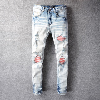 AMIRI heavy wash light-colored ripped red patch slim jeans