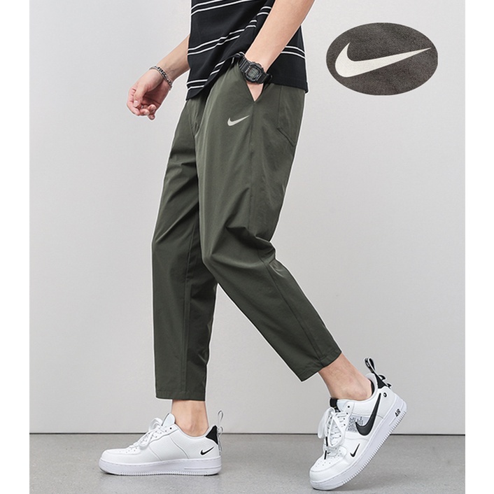 Nike ของแท้ 100% กางเกงวอร์ม ผ้าไนล่อน สี่ด้าน พิมพ์ลายโลโก้สะท้อนแสง สไตล์มินิมอล สําหรับผู้ชาย ผู้หญิง