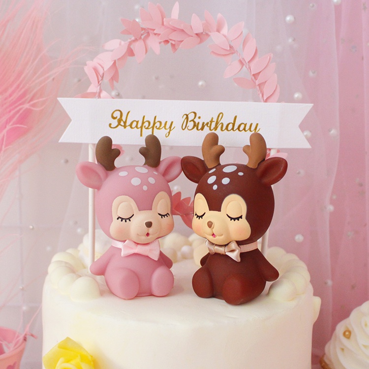 ตุ๊กตากวางสีชมพูและสีน้ําตาลตกแต่งเค้กวันเกิดด้านบน