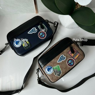 กระเป๋าสะพายข้างผู้ชาย 💕GRAHAM CROSSBODY WITH TRAVEL PATCHES F72945 005