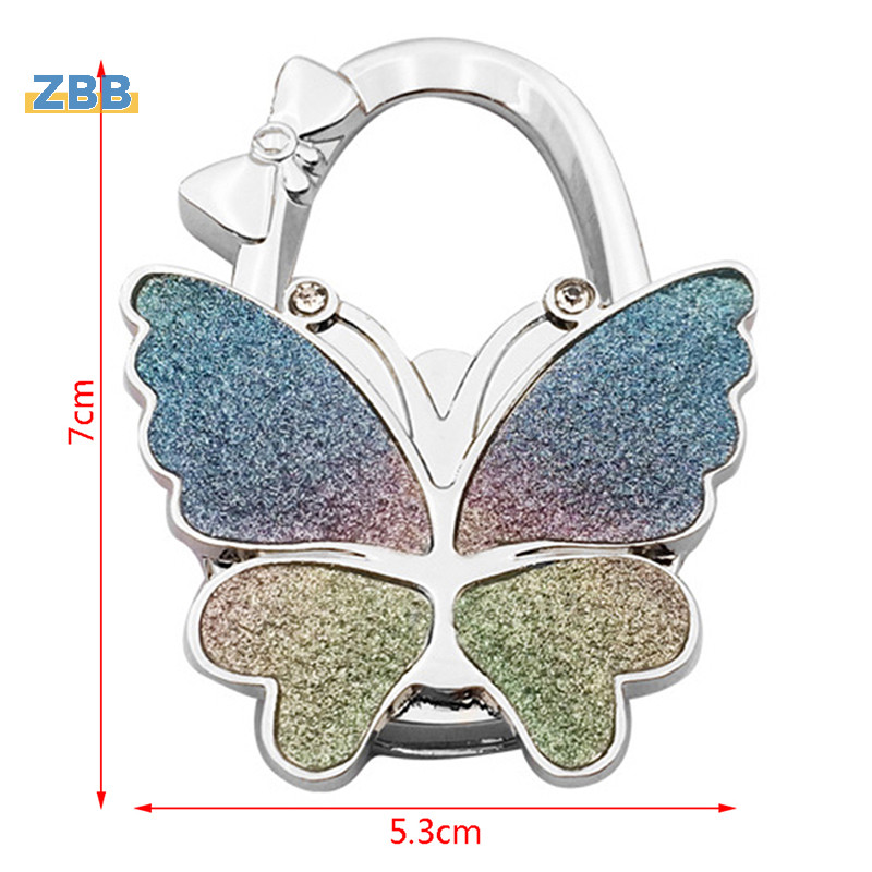 Zbb> ใหม่ ตะขอแขวนกระเป๋าถือ รูปผีเสื้อ พับได้ แบบพกพา อุปกรณ์เสริม สําหรับแขวนกระเป๋า