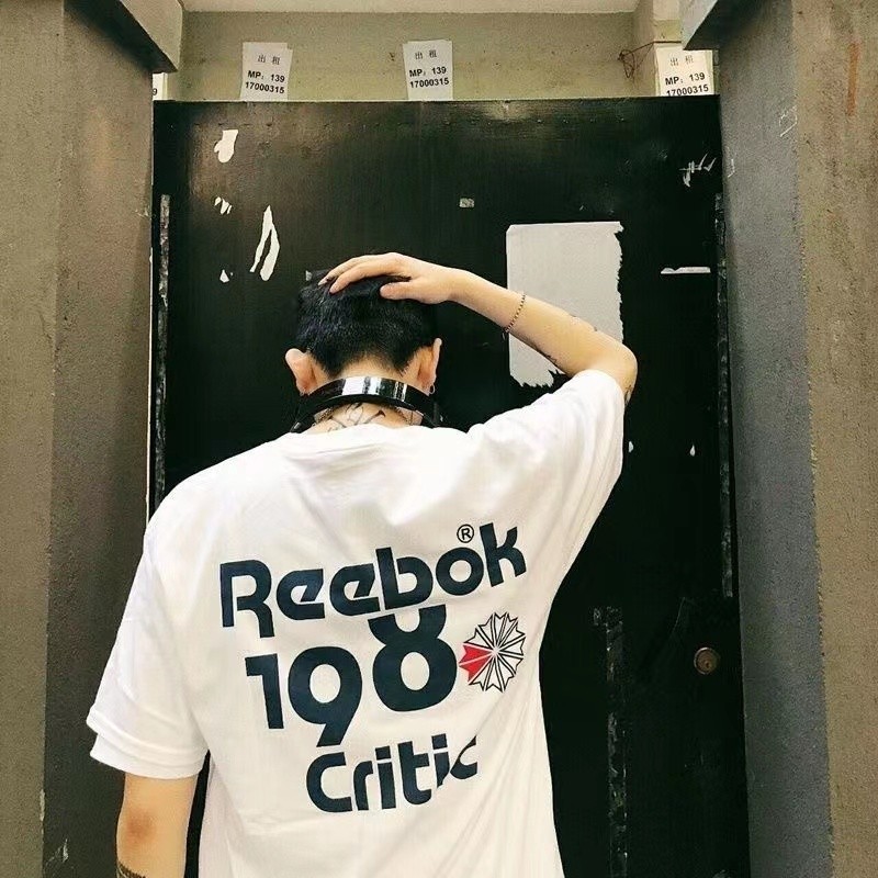 พร้อมสต็อก REEOK เสื้อยืดคอกลมแขนสั้นสําหรับผู้ชายและผู้หญิงคู่รักตัวอักษรหลวม