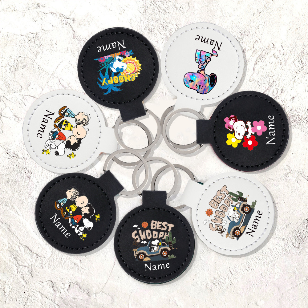 Snoopy พิมพ์การ์ตูนที่กําหนดเองชื่อ PU พวงกุญแจหนัง Circulaire พวงกุญแจพวงกุญแจรถเครื่องประดับกระเป๋าอุปกรณ์เสริมของขวัญที่กําหนดเองที่ดีที่สุด