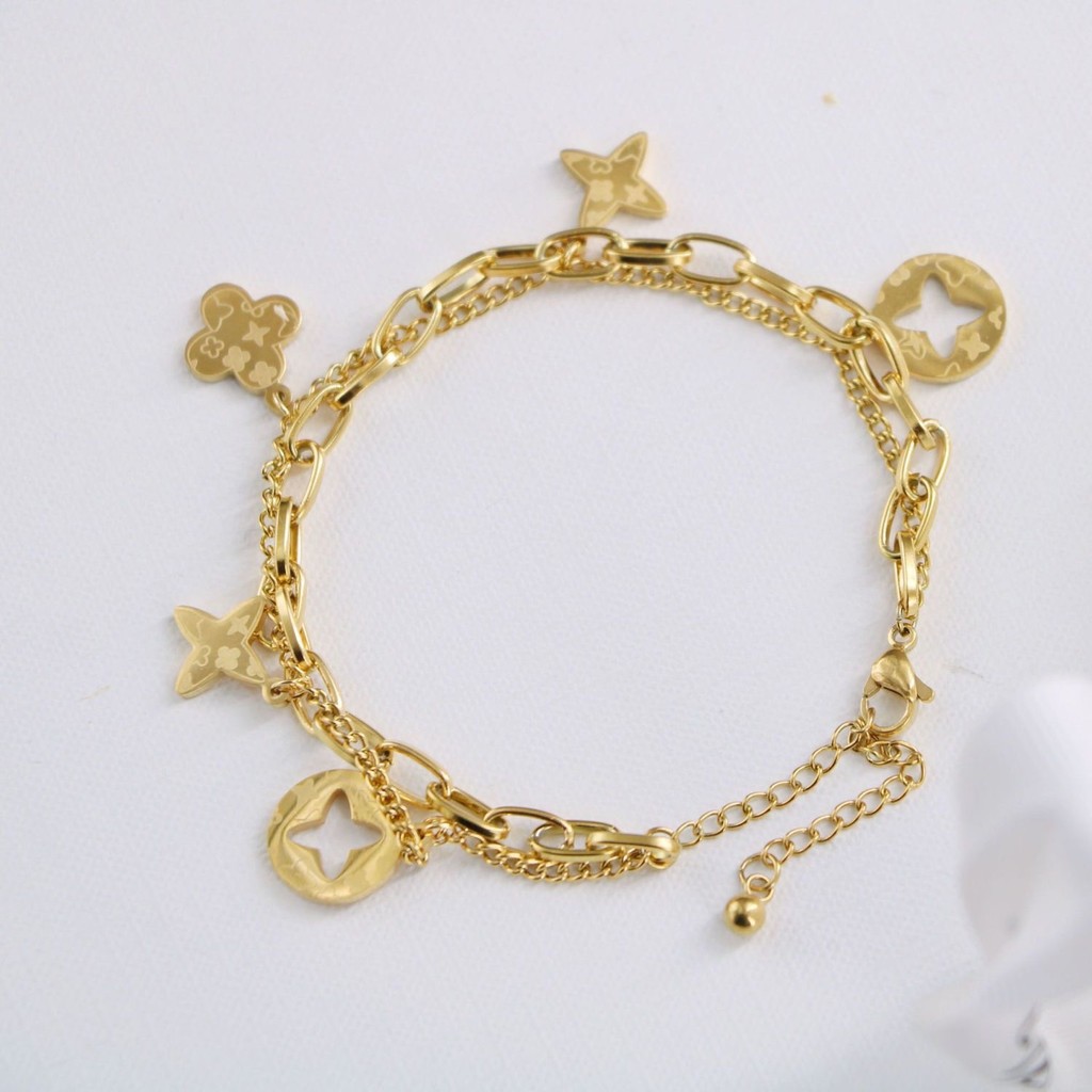 สร้อยข้อมือพู่ใบโคลเวอร์สี่ใบกลวงสีทองสไตล์ฮิตข้ามพรมแดนสำหรับผู้หญิงไม่ซีดจางแฟชั่นญี่ปุ่นและเกาหลีเครื่องประดับดอกไม้ปริซึม