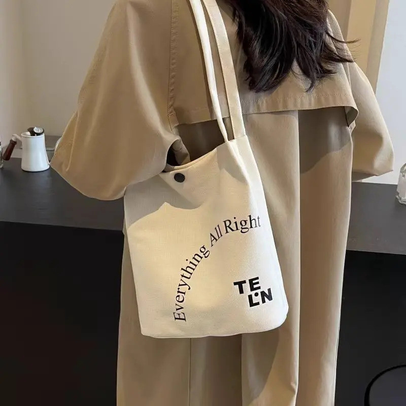 กระเป๋า Tote ทำจากผ้าแคนวาสมากำมะโดะ สไตล์เรียบง่ายแต่มีเอกลักษณ์ มาพร้อมลายอักษรปลอมและมีหลายแบบให้เลือก พกพาสะดวก