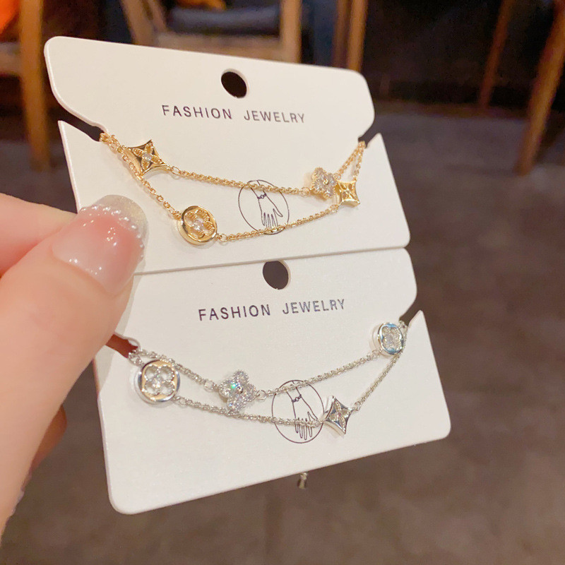 สร้อยข้อมือดีไซน์เรียบหรู มีสองชั้นและประดับด้วยดอกไม้สี่แฉก