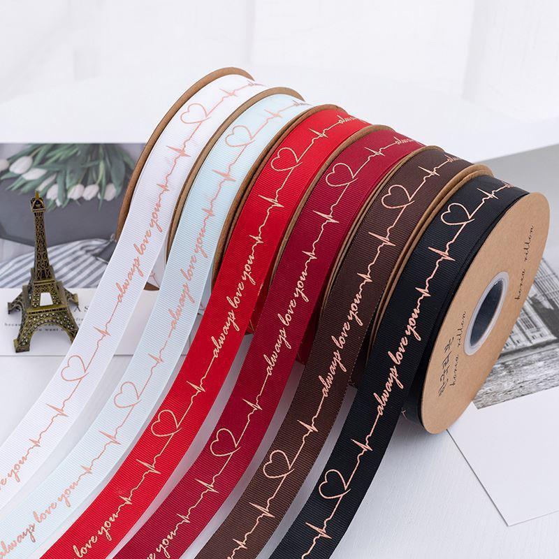 ริบบิ้นลายตัวอักษรและชีพจรหัวใจขนาด2.5 cm ยาว 50 หลา ( 1หลา=0.914 เมตร) สำหรับตกแต่ง ผูกโบว์ ห่อของขวัญ ห่อช่อดอกไม้