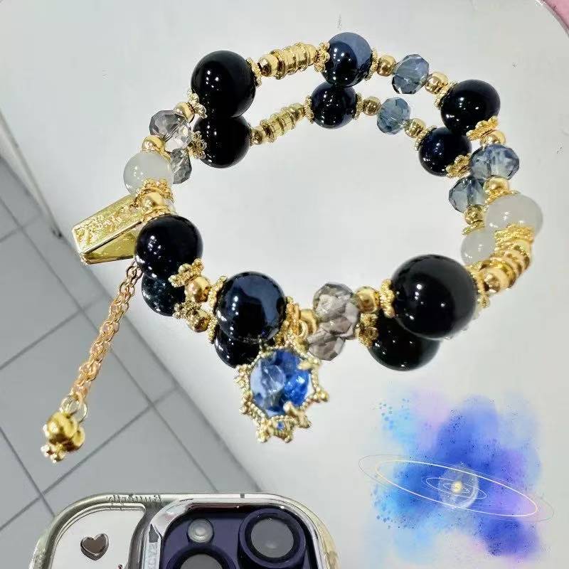 สร้อยข้อมือประณีต โทนสีดำ ทอง และน้ำเงินเข้ม มีลวดลายคล้ายทราย พร้อมความหรูหรา