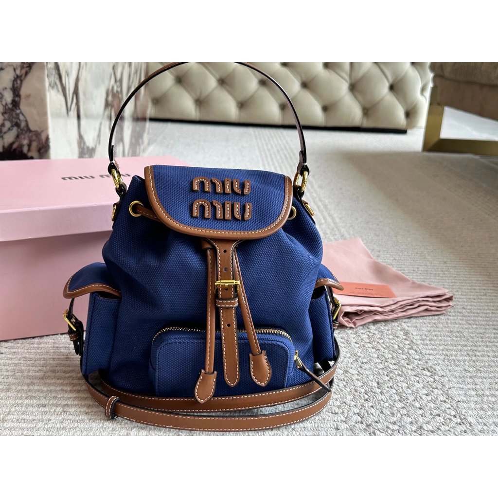 Miumiu กระเป๋าเป้สะพายหลัง 25ss กระเป๋าเป้สะพายหลัง Preppy สไตล์ผู้ชายผู้หญิงสไตล์เดียวกันกระเป๋านัก
