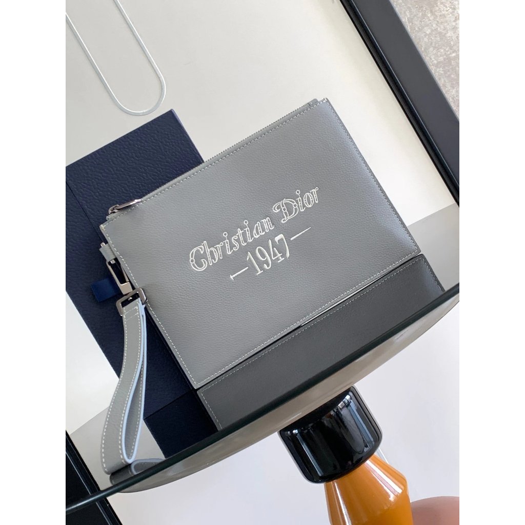 คลัช Dior สีเทา ทำจากหนังวัว ออกแบบอย่างเรียบง่ายแต่หรูหรา มาพร้อมโลโก้ Christian Dior 1947 และมีซิป