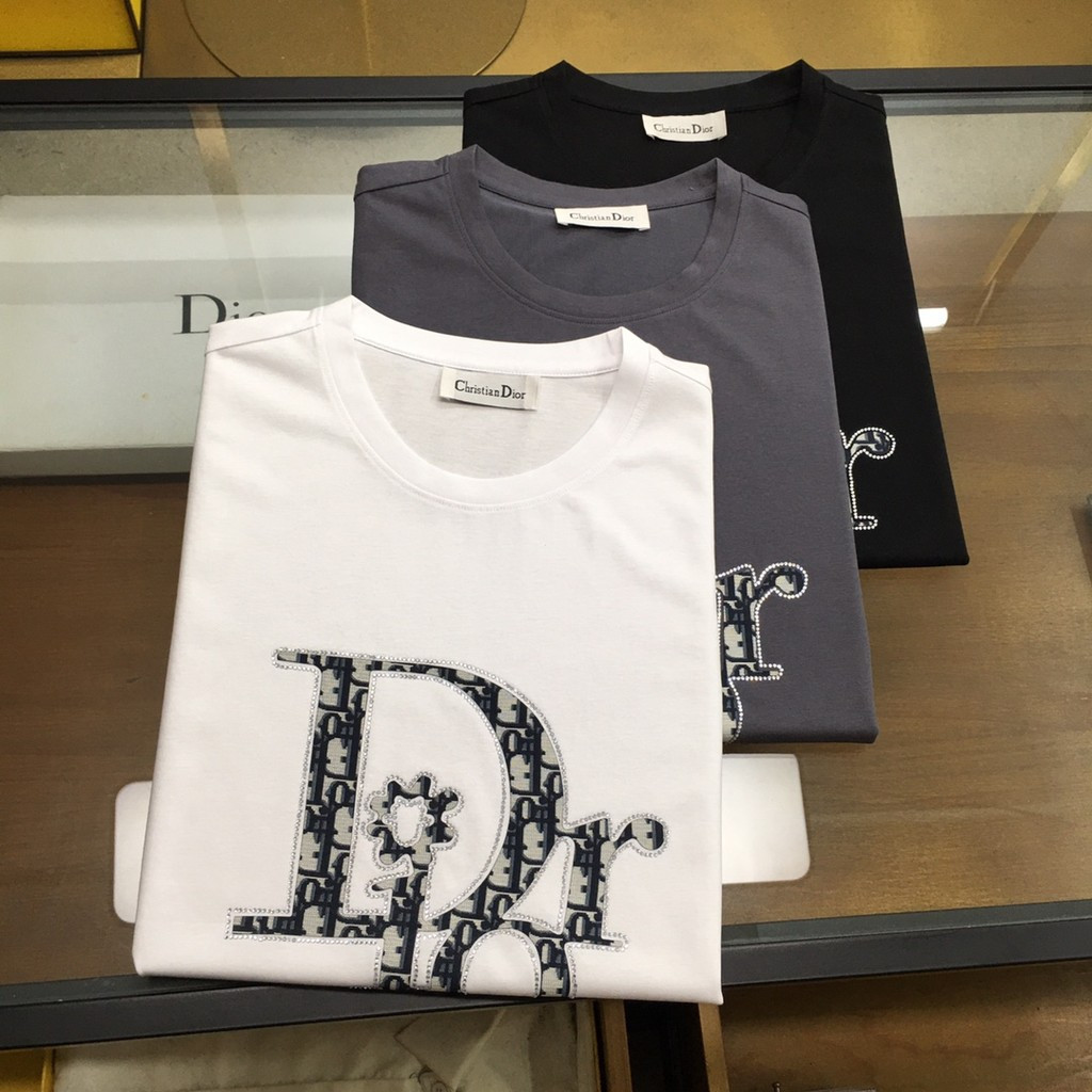 เสื้อยืด DIOR แบบคลาสสิกรอบคอมีลายแขนสั้น ออกแบบมาสำหรับทั้งผู้ชายและผู้หญิง มาพร้อมไหล่หนาและทรงกระ
