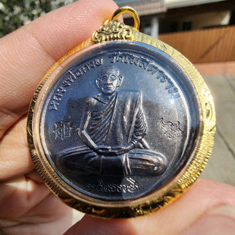 เหรียญหลวงพ่อกวย วัดโฆสิตาราม เหรียญกลมมงคลถาวร ปี 2555 เนื้อทองแดงรมดำ หลังยันต์มงกุฎพระเจ้า เลี่ยมกันน้ำ