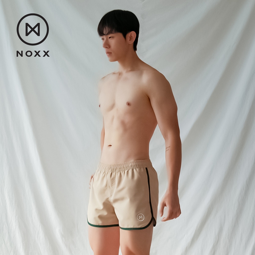 Noxx Swim Trunks: กางเกงว่ายน้ำ ขาสั้น แบบทรังค์ สีครีม Nude กุ๊นเขียว