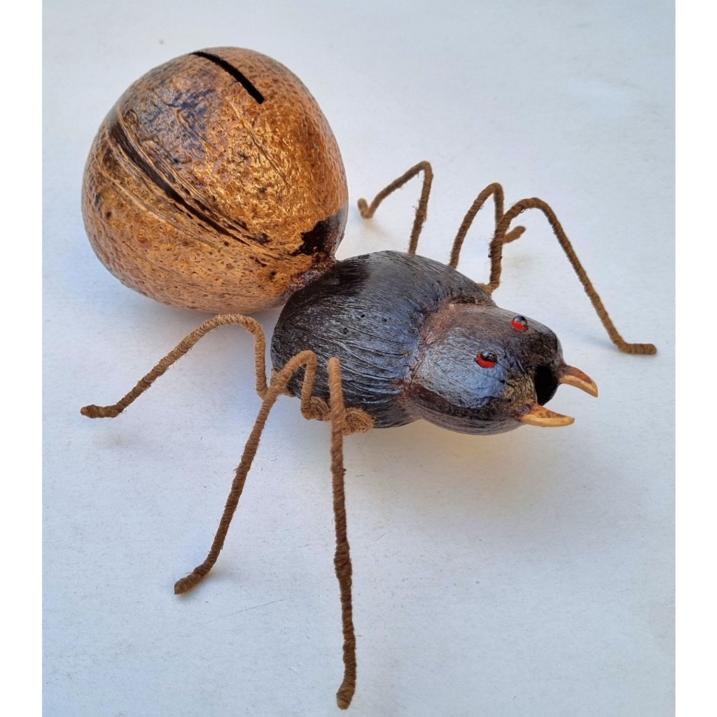 กระปุกออมสิน (มด) ยาว 19.5 ซม. กว้าง 15 ซม. ทำด้วยกะลามะพร้าว งานฝีมือจากภูมิปัญญาชาวบ้าน สำหรับออมเงิน/ตกแต่ง