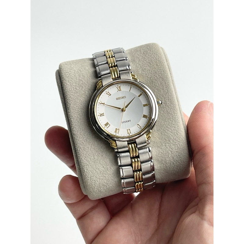 Seiko Lucent   “ตัวเรือนสองกษัตริย์ หน้าปัดเงินของครีม หลักเวลาเลขโรมันสีทอง ชุดเข็มดาบสีทอง เม็ดมะย