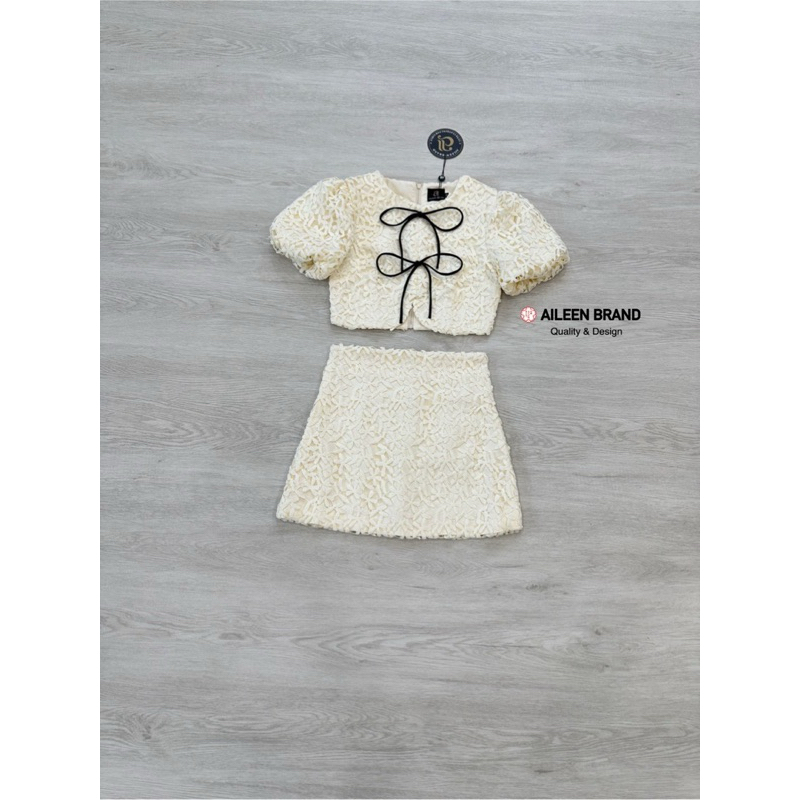 Aileen เสื้อคอป ลูกไม้สีครีม แขนสั้น แต่งจั้มสม๊อคแขน ดีเทลแต่งสายผู้โบว์หน้า มีซิปหลัง แมทซ์กับกระโปรงสั้นลูกไม้