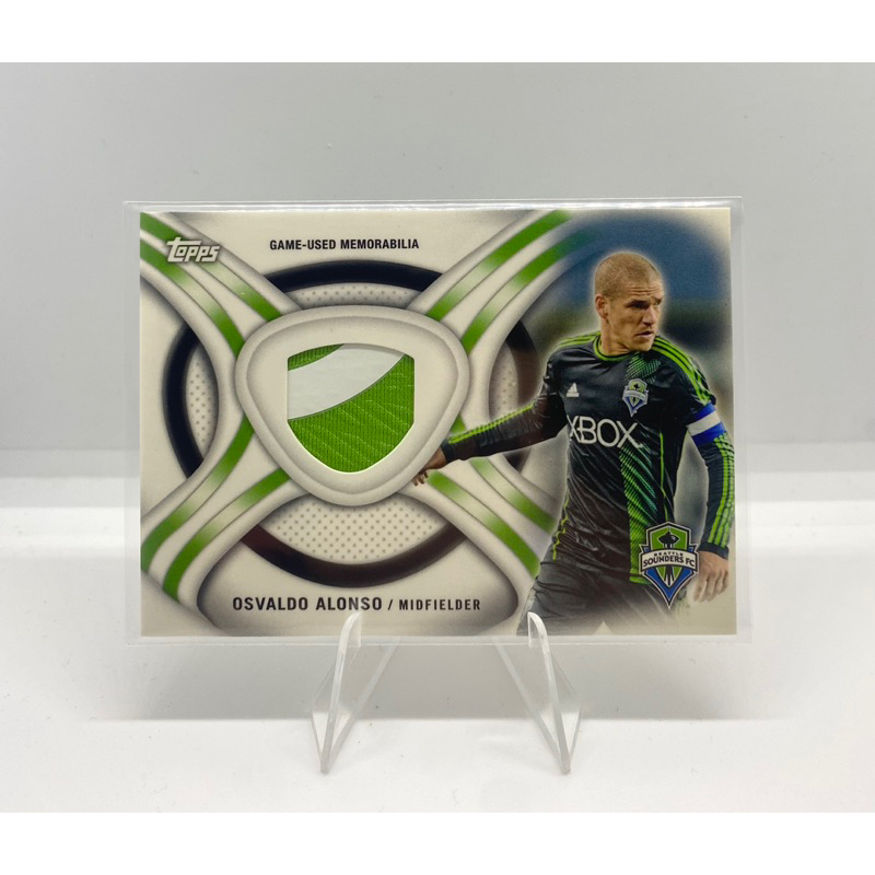 การ์ดฟุตบอล👕ชิ้นส่วนผ้า OSVALDO ALONSO MIDFIELDER GAME-USED MEMORABILIA 2013 Topps MLS Relics