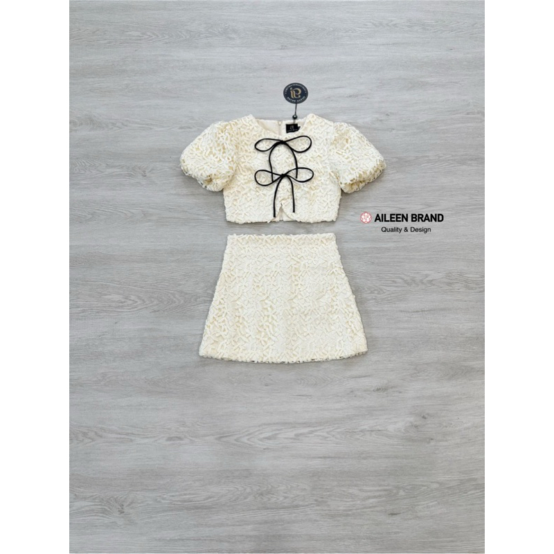 Aileen เสื้อคอป ลูกไม้สีครีม แขนสั้น แต่งจั้มสม๊อคแขน ดีเทลแต่งสายผู้โบว์หน้า มีซิปหลัง แมทซ์กับกระโปรงสั้นลูกไม้