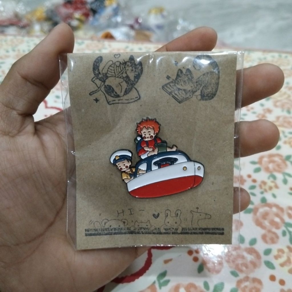 เข็มกลัดโลหะเคลือบอีนาเมลลาย Ponyo และ Sosuke จากเรื่อง Ponyo บนเรือของเล่น ตามที่ระบุในรายการ
