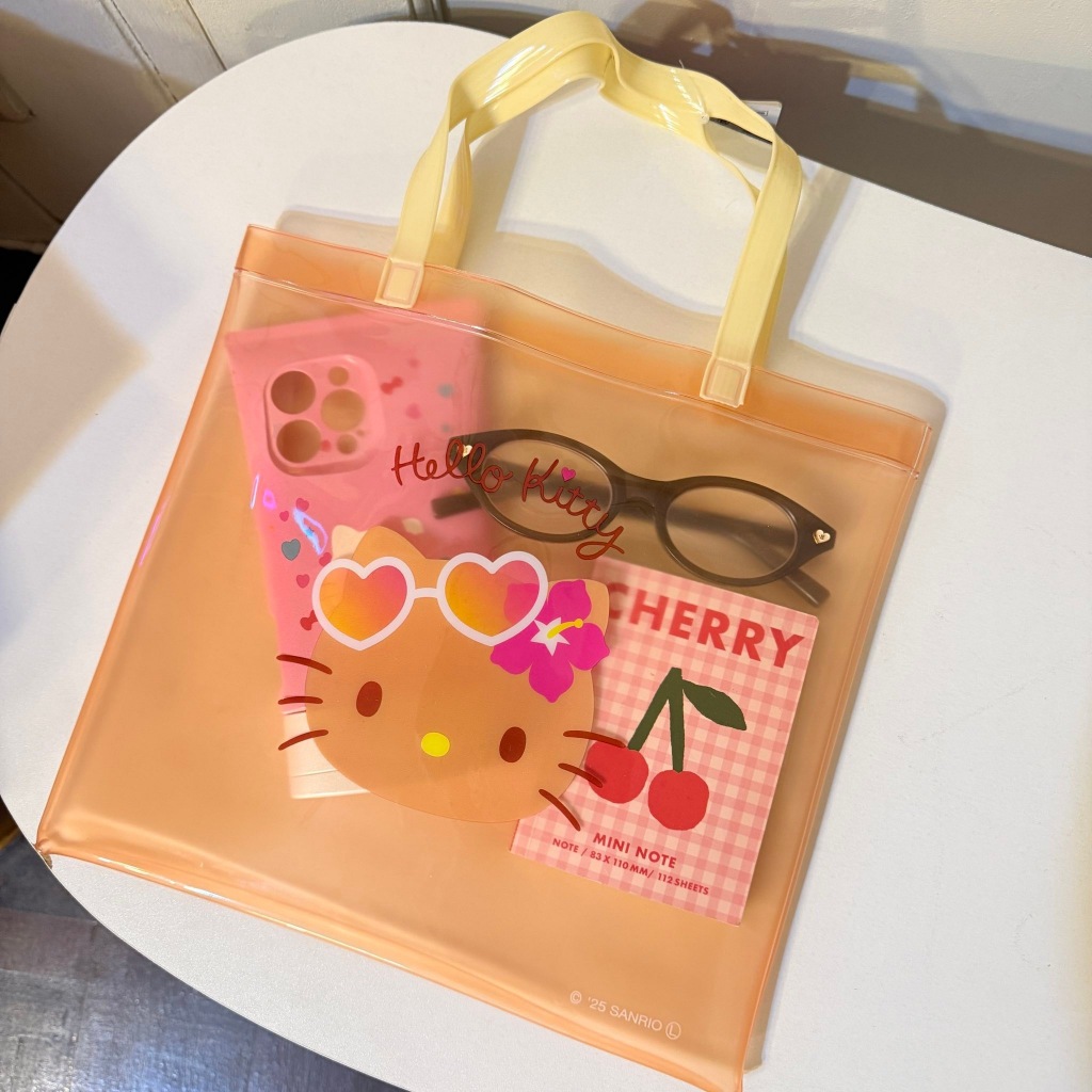 กระเป๋าถือ PVC ใสลาย Hello Kitty ผิวสีแทนจาก Sanrio มาพร้อมหูหิ้วสีเหลืองอ่อน