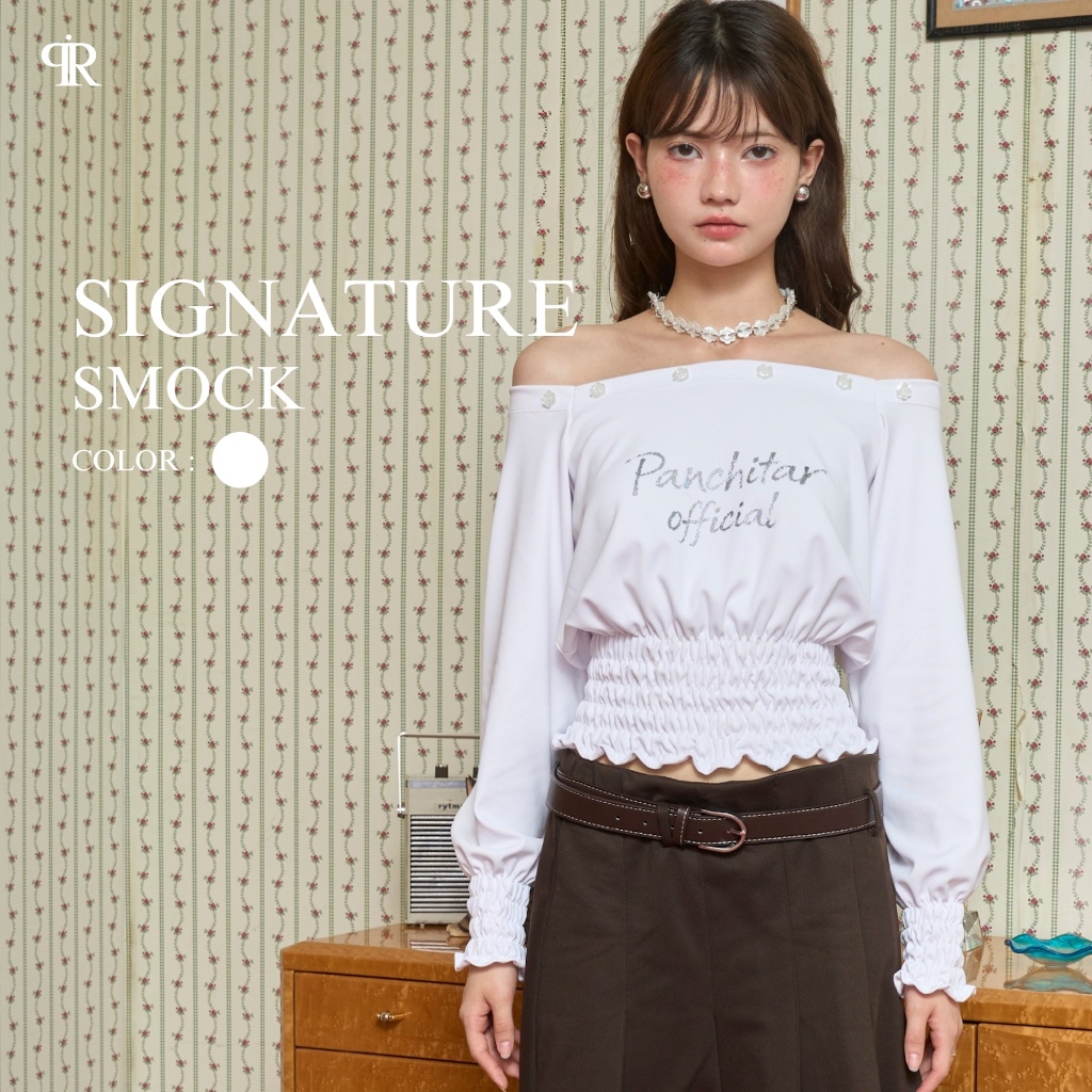 Panchitar Signature Smock – เสื้อสีขาวทรงเปิดไหล่ ดีเทลสกรีนโลโก้ที่หน้าอก มีสม็อกช่วงเอวและปลายแขน