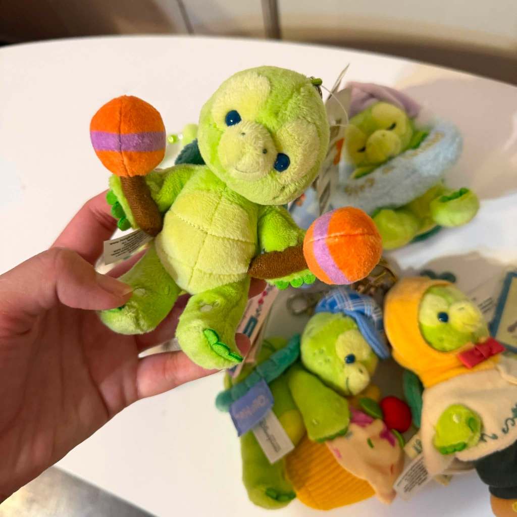 พวงกุญแจตุ๊กตาเต่าเขียว Olu Mel จากคอลเลกชัน Duffy and Friends ในชุดถือเครื่องดนตรีมารากัสสีส้มและม่