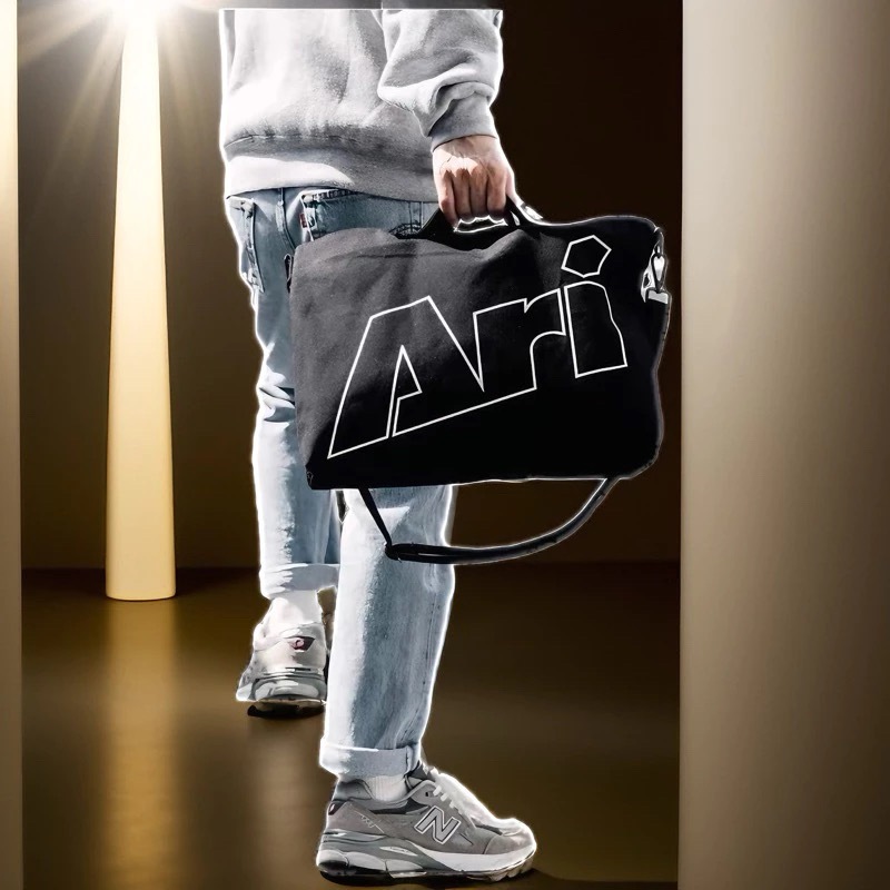 Ari กระเป๋าสะพายไหล่ ARI SHOULDER BAG สีดำ วัสดุผ้าแคนวาส สายสะพายปรับได้ ดีไซน์เรียบง่าย ทนทาน พร้อมโลโก้ Ari ด้านหน้า