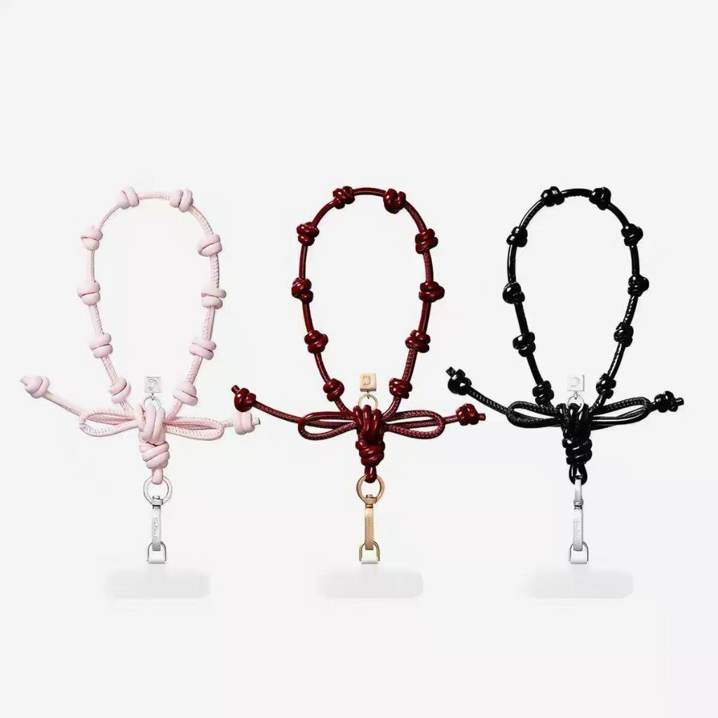 CASETiFY's new leather wristband with bow detail in pink/black/wine red, featuring a hanging decorative key ring, phone