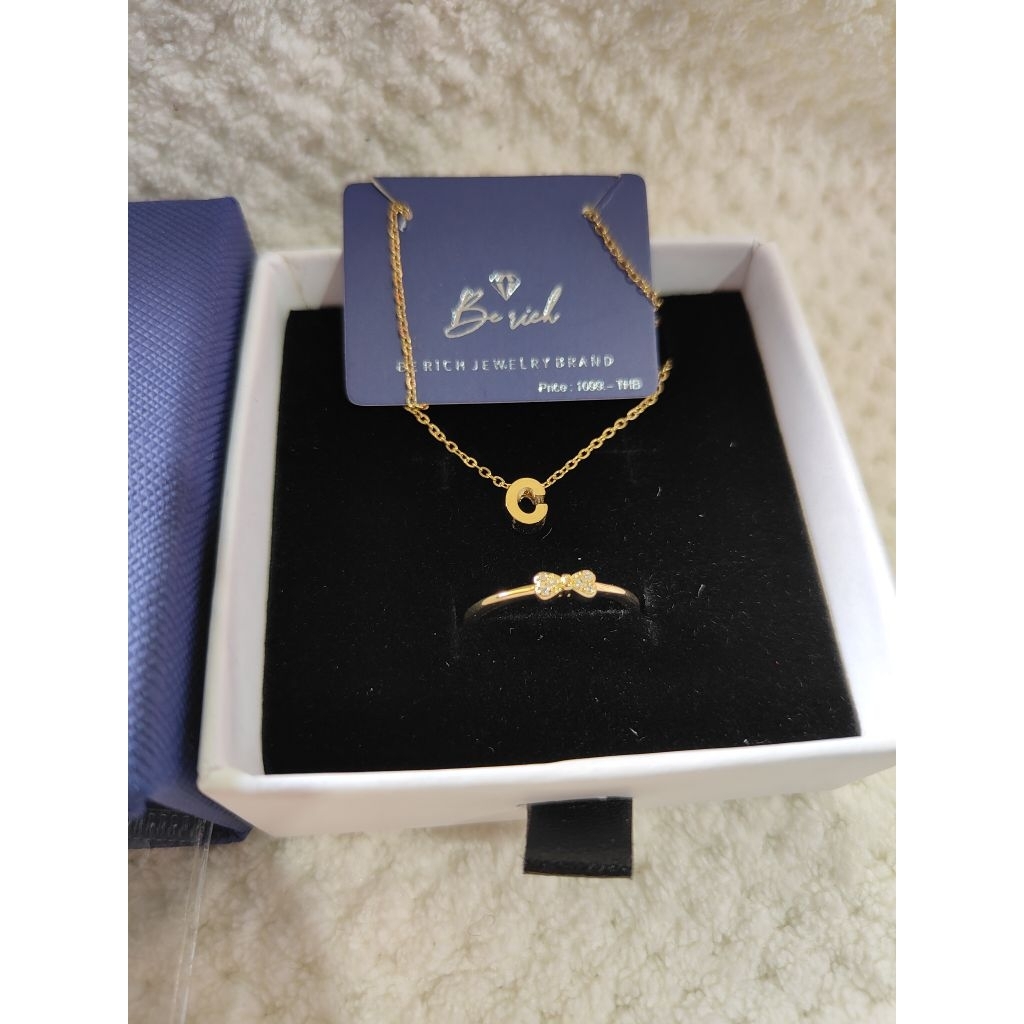 เครื่องประดับจากแบรนด์ BE RICH ประกอบด้วยสร้อยคอจี้ตัวอักษร "C" และแหวนประดับโบว์เล็ก.