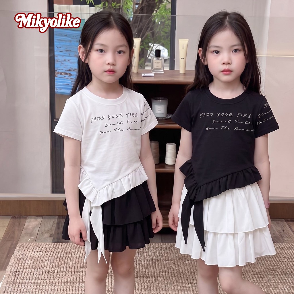 Mikyolike 4-14 ปี เสื้อยืดเด็กผู้หญิงแขนสั้น ลายตัวอักษร ขอบริ้วไม่สม่ำเสมอ มีโบว์ห้อย แฟชั่นเกาหลี ผ้านุ่ม 2 สี ขาวดำ